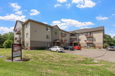 an apartment building with a sign in front of a parking lot