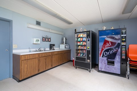 a snack room with a vending machine and a sink and a coke refrigerator