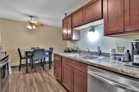 A kitchen with brown cabinets and a stainless steel sink.