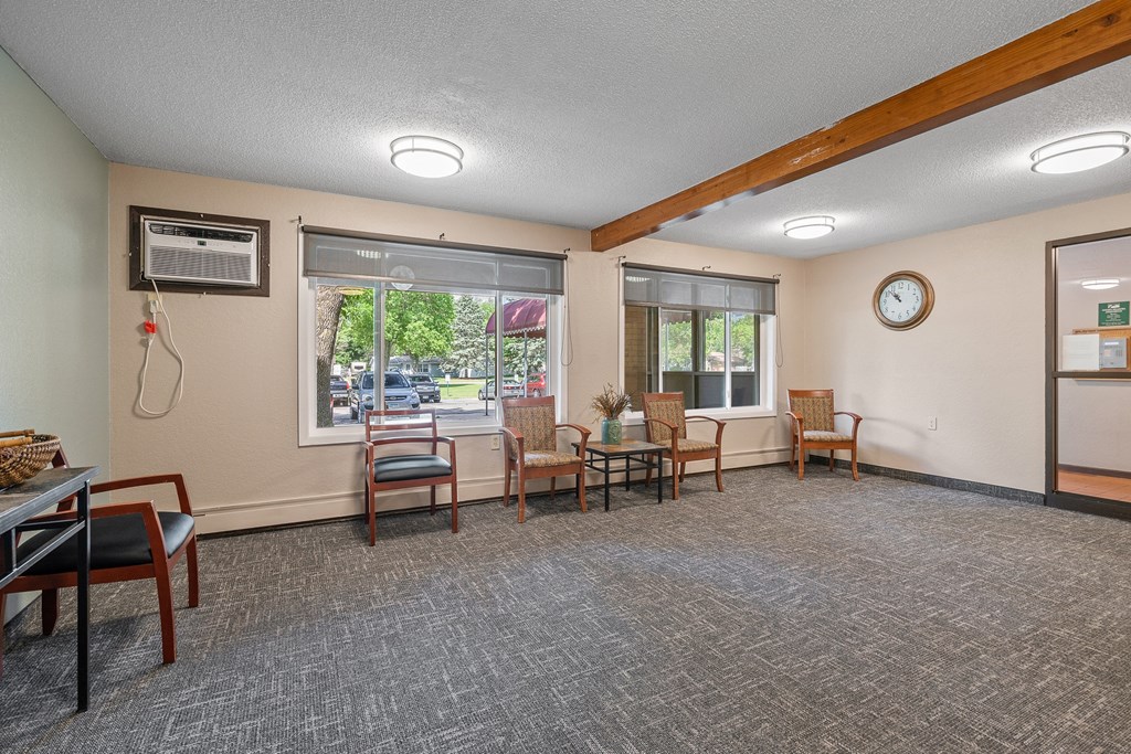 a common room with chairs and a table and a clock on the wall