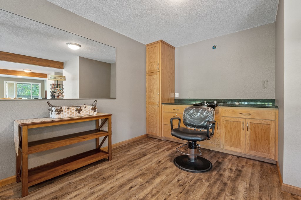 a living room with a chair and a kitchen with a sink