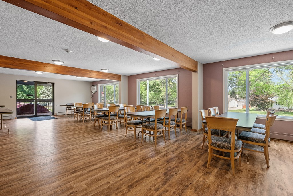 a community room with tables and chairs and large windows
