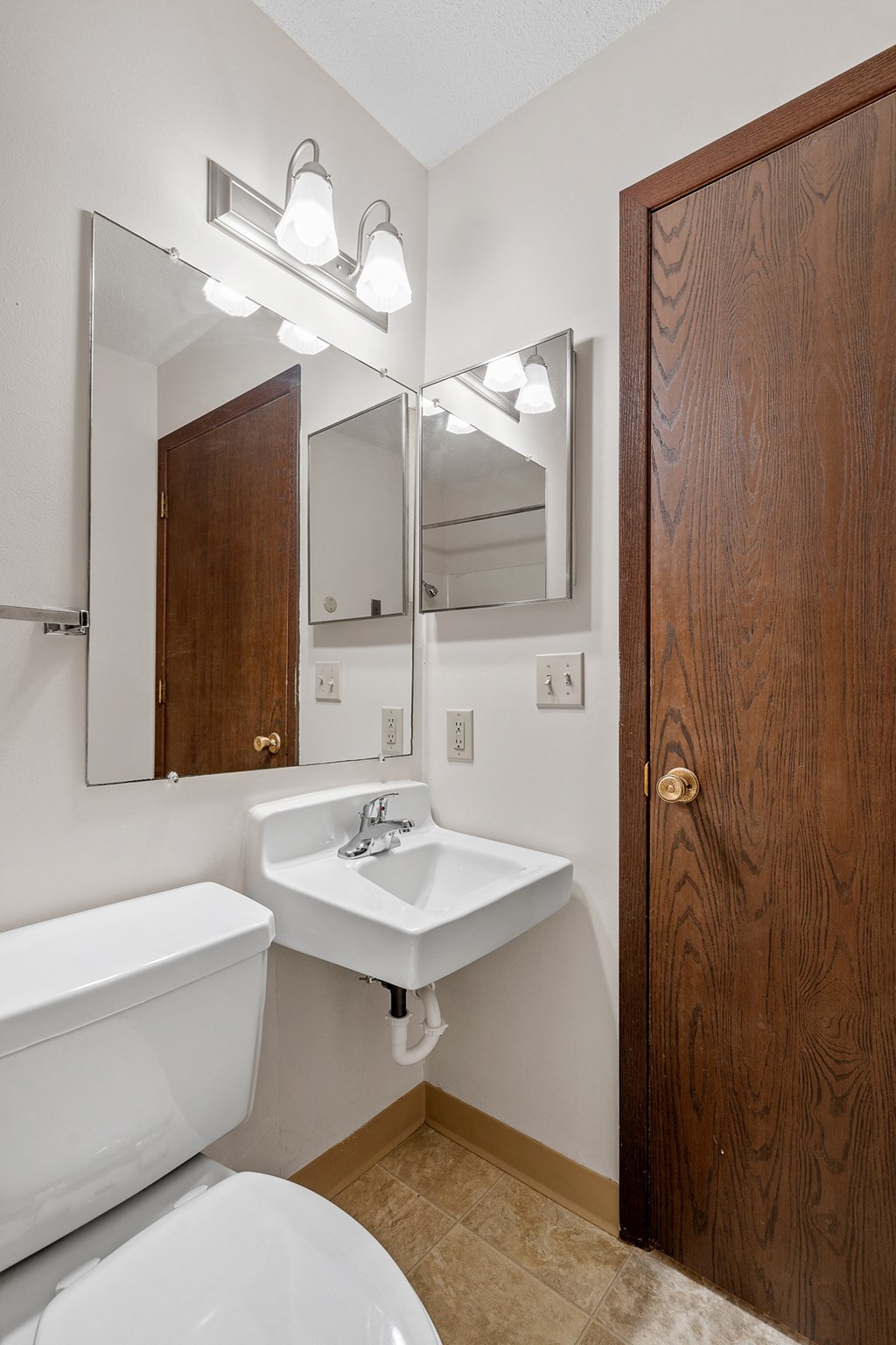 a bathroom with a toilet sink and mirror and a wooden door