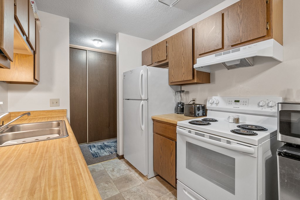 a kitchen with white appliances and wooden cabinets and a white refrigerator