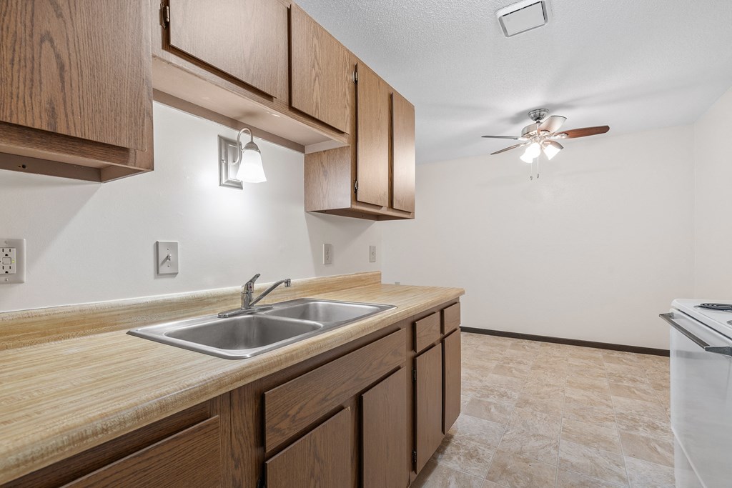 an empty kitchen with a sink and a ceiling fan