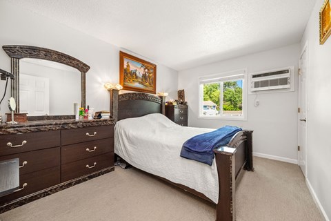 A bedroom with a bed, dresser, and mirror.