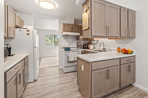 A kitchen with a white refrigerator and brown cabinets.