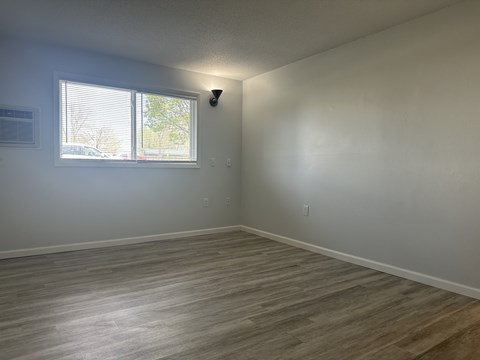 A room with a window and a light on the wall.