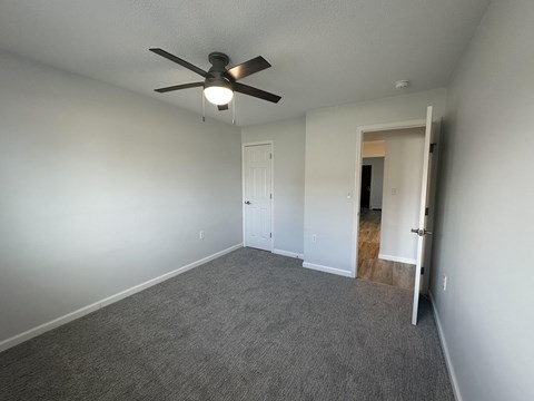 A room with a ceiling fan and carpeted floor.