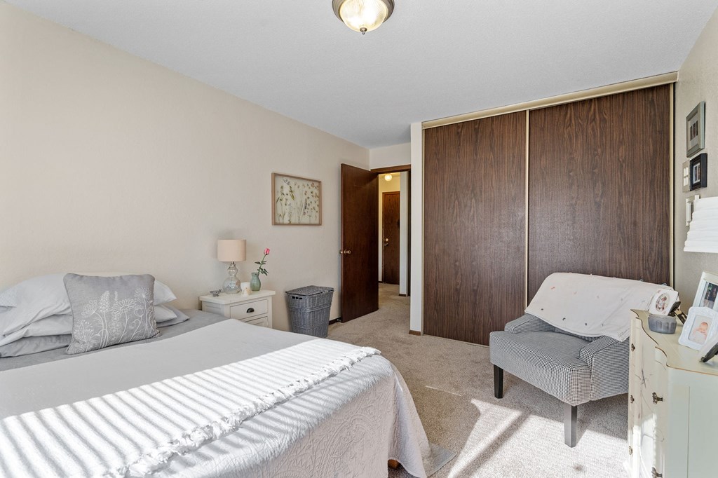 a bedroom with a bed and a chair and a closet