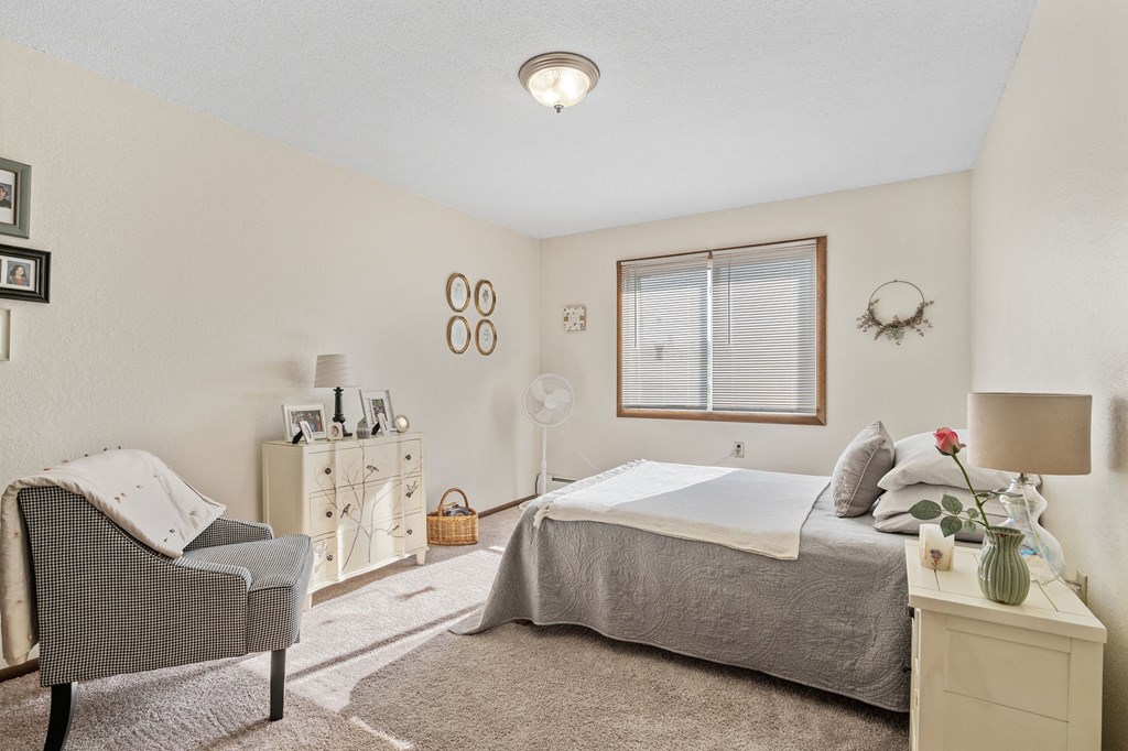 a bedroom with a bed and a chair and a window