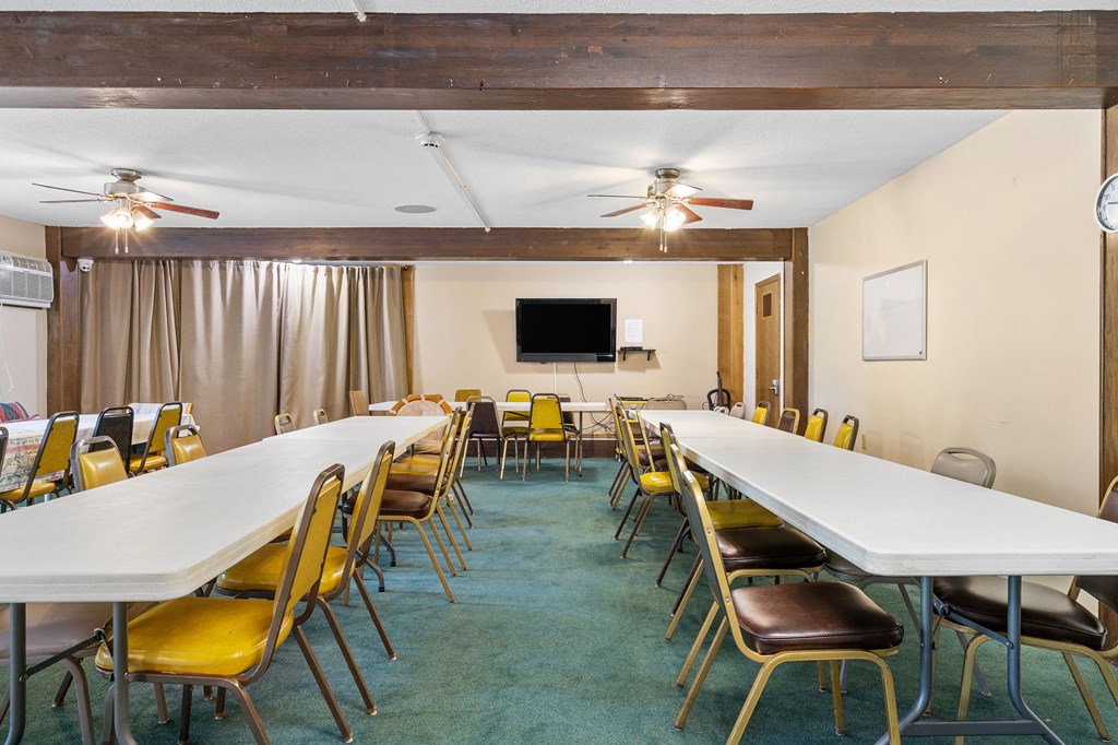 a conference room with long tables and chairs and a tv