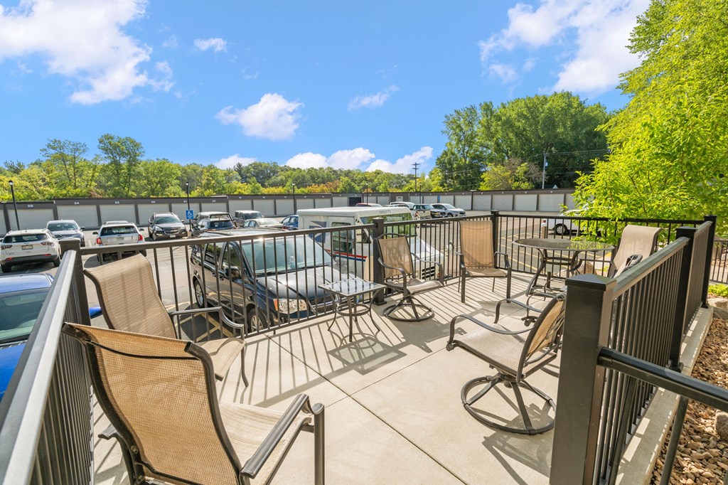 a patio with chairs and tables on a balcony with a parking lot