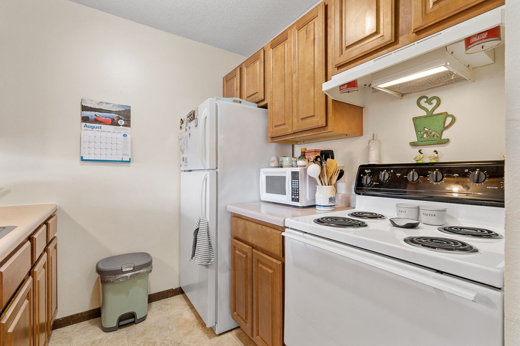 a kitchen with white appliances and wooden cabinets and a white refrigerator