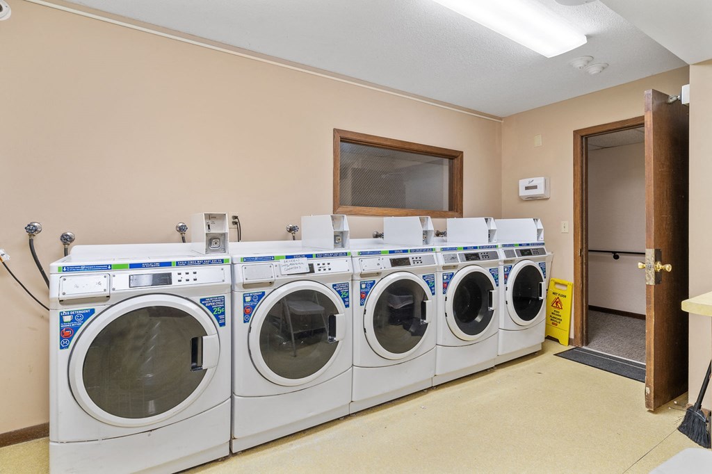 a washer and dryer in a laundry room with four washing machines
