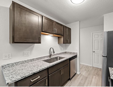 A kitchen with brown cabinets and granite countertops.