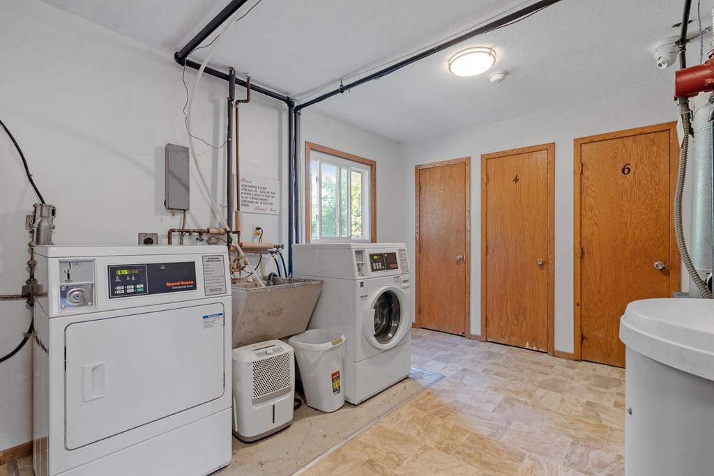 a laundry room with two washer and dryers and a sink