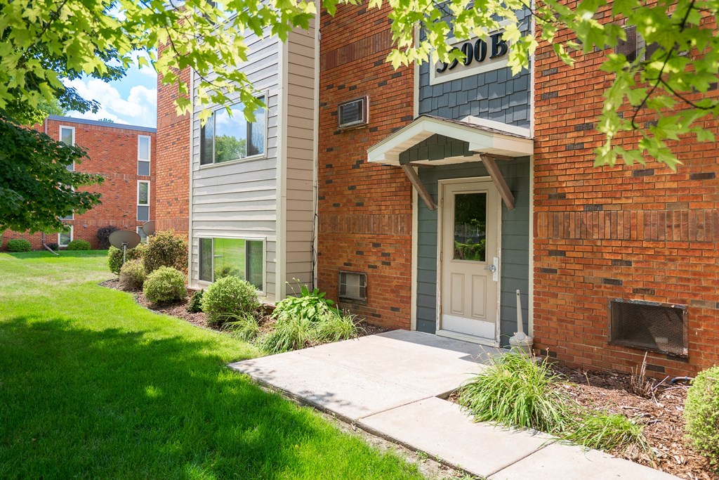 the sidewalk in front of a brick building with a white door