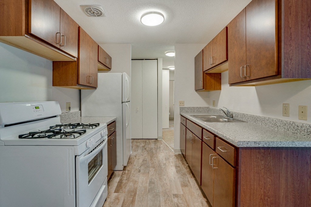a kitchen with wood cabinets and white appliances and a counter top with a stove and
