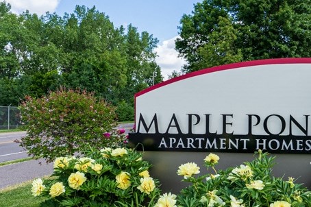 a sign for maple point apartments with yellow and white flowers
