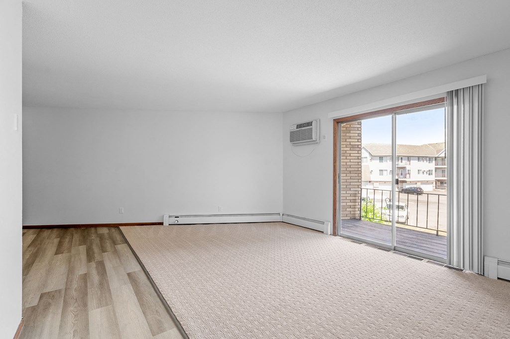 an empty living room with a sliding glass door to a balcony