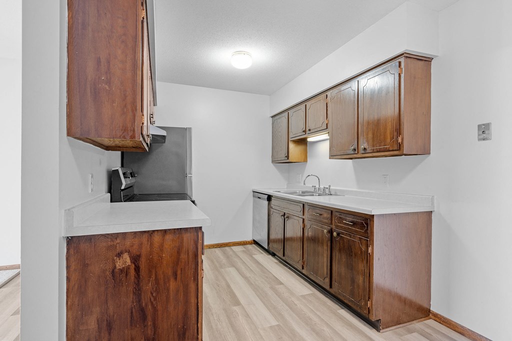 a kitchen with wooden cabinets and a sink and a refrigerator