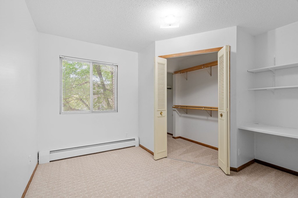 a bedroom with a closet and a window and a bathroom