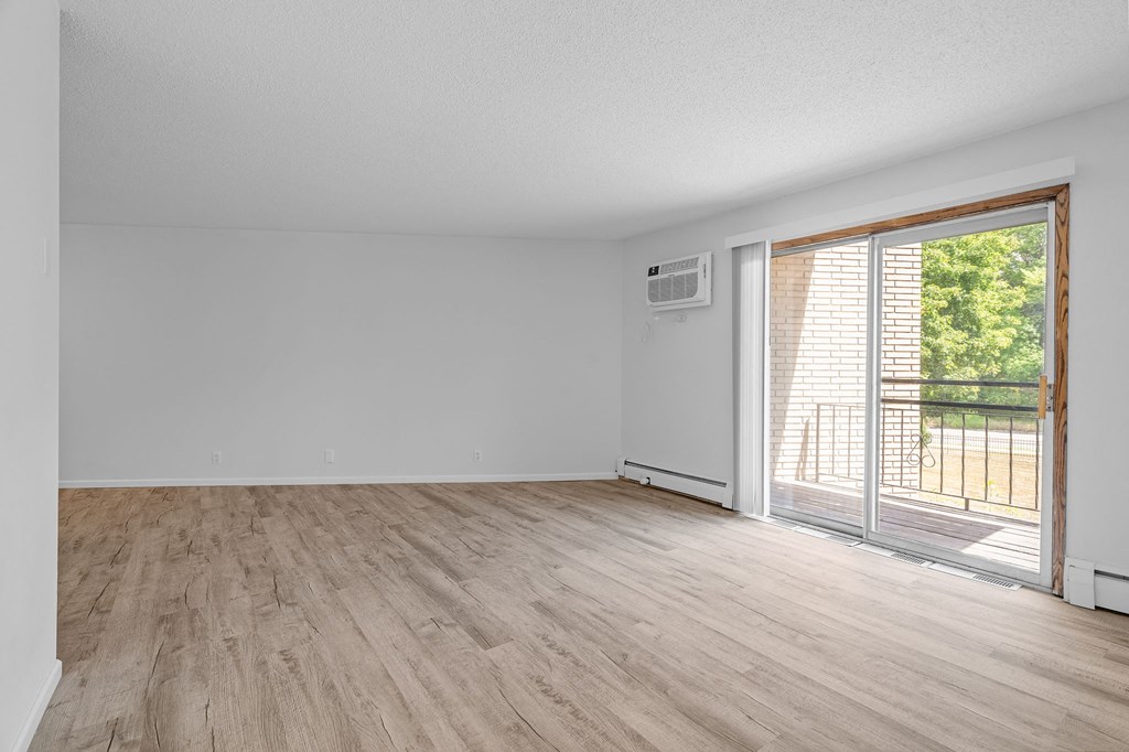 an empty living room with a sliding glass door to a balcony
