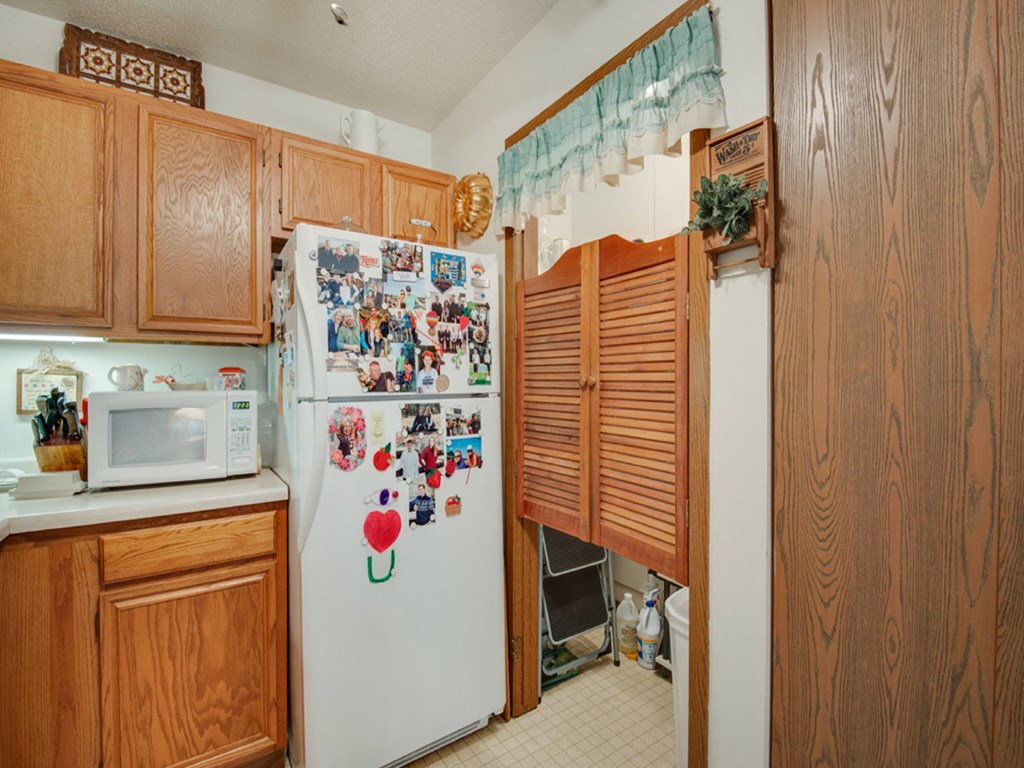 a kitchen with a white refrigerator and wooden cabinets