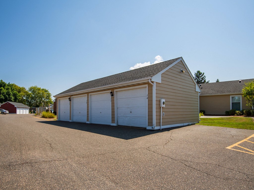 a small garage with white doors on the side of a road
