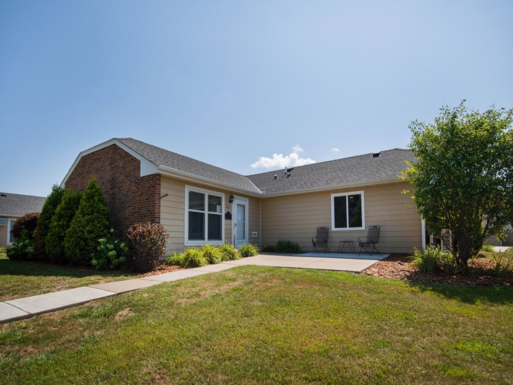 a tan house with a lawn and a sidewalk