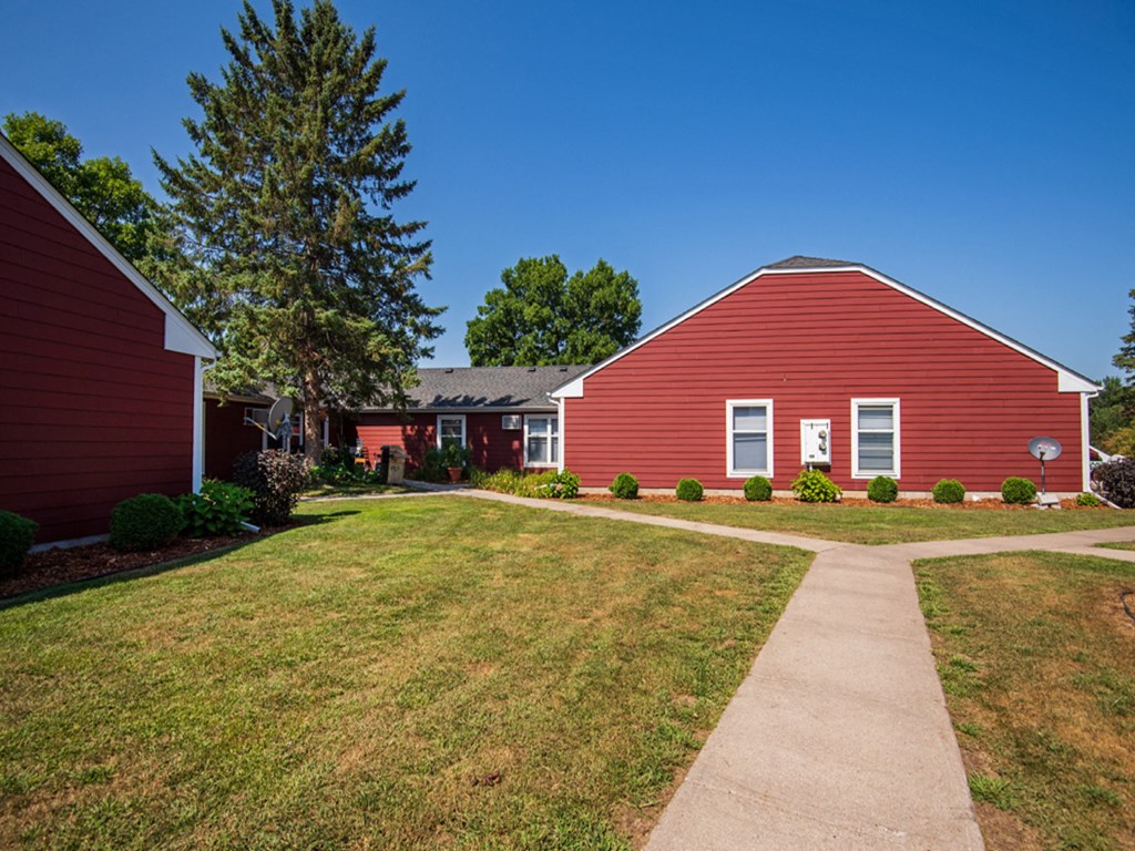 a red barn with a sidewalk in front of it