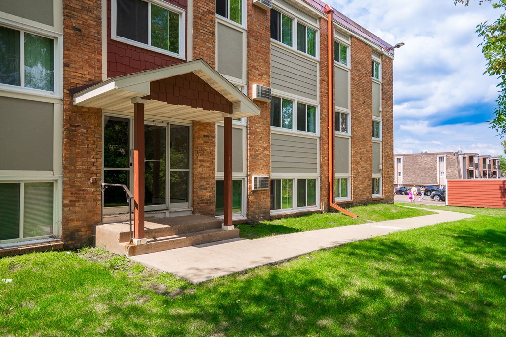 a brick building with a porch and a sidewalk in front of it