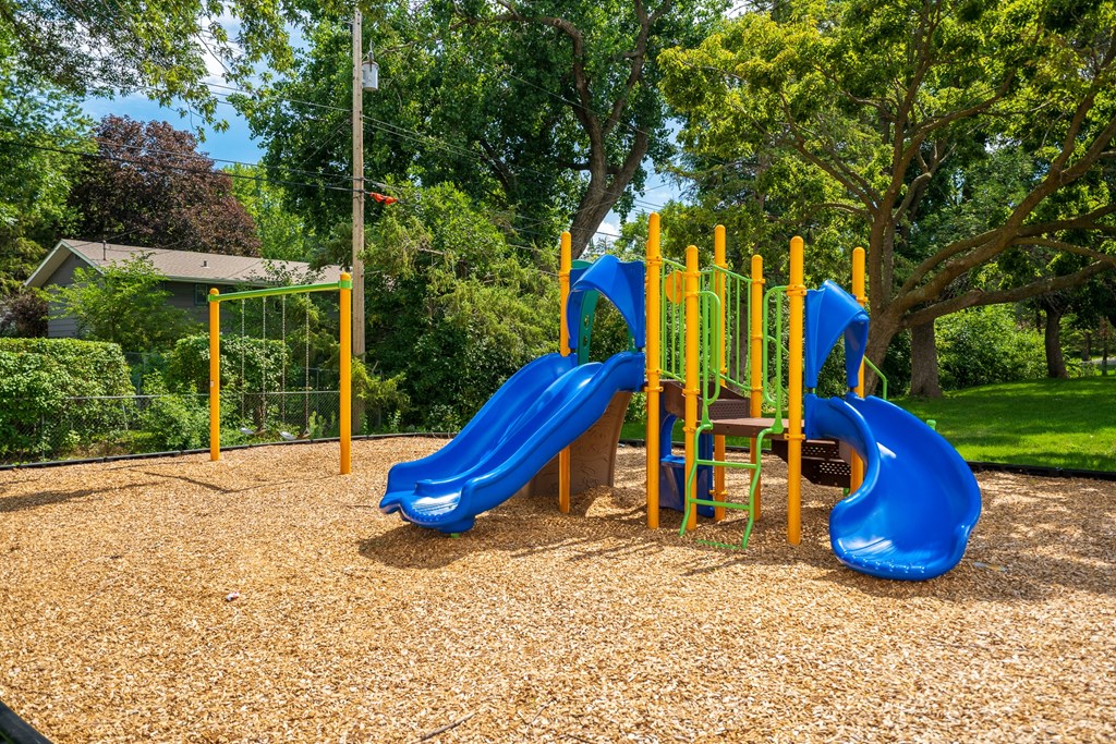 a playground with two blue slides and a yellow swing set