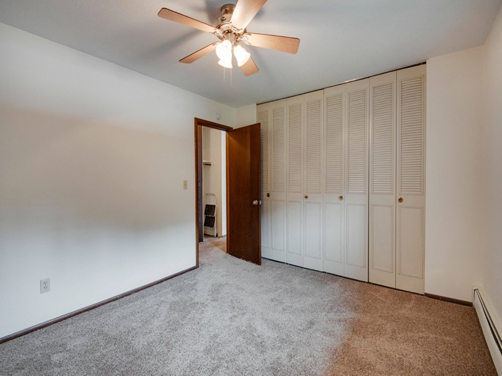 an empty living room with carpet and a ceiling fan