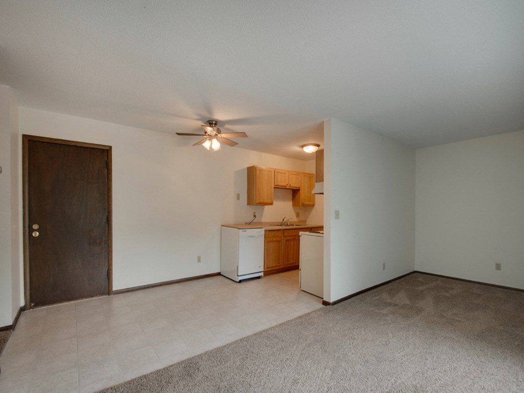 an empty living room and kitchen with a ceiling fan