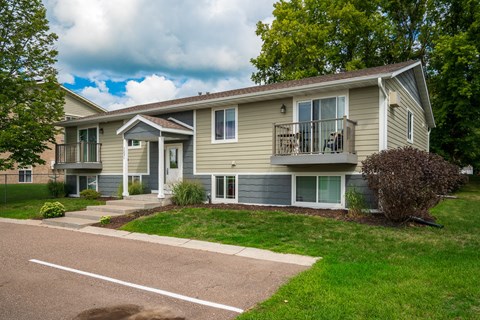 a beige house with a porch and a sidewalk