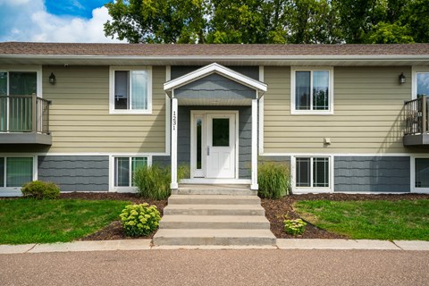 A two-story residential building with a front porch and a white door.