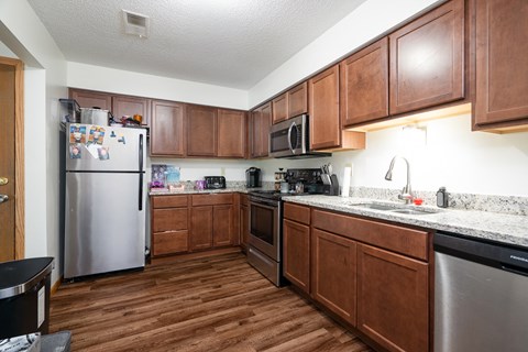 A kitchen with wooden cabinets and a stainless steel refrigerator.