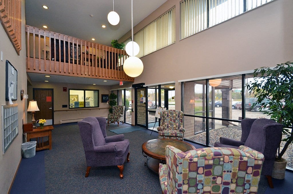 A living room with a purple chair and a multicolored ottoman.