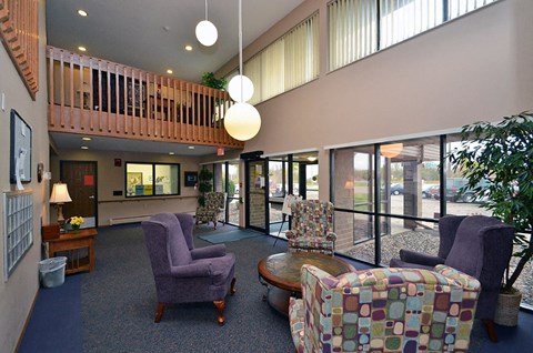 A living room with a purple chair and a multicolored ottoman.