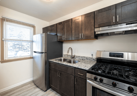 A kitchen with a stainless steel refrigerator, sink, and stove.