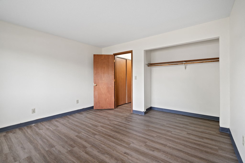 an empty living room with wood flooring and a door to a closet