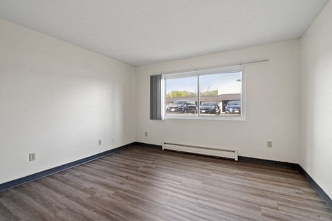 the living room of a new home with wood flooring and a window
