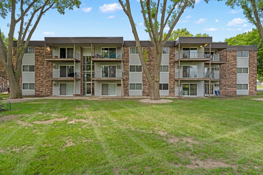 an apartment building with green grass and trees in front of it
