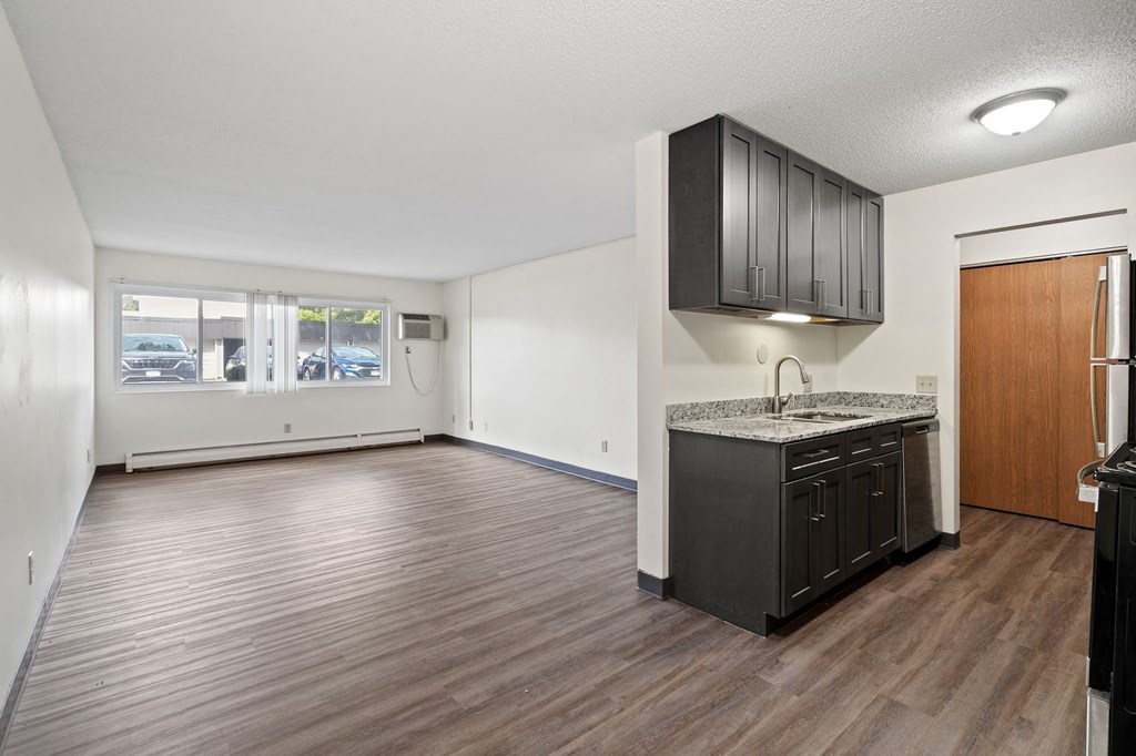 an empty kitchen and living room with a refrigerator and a sink