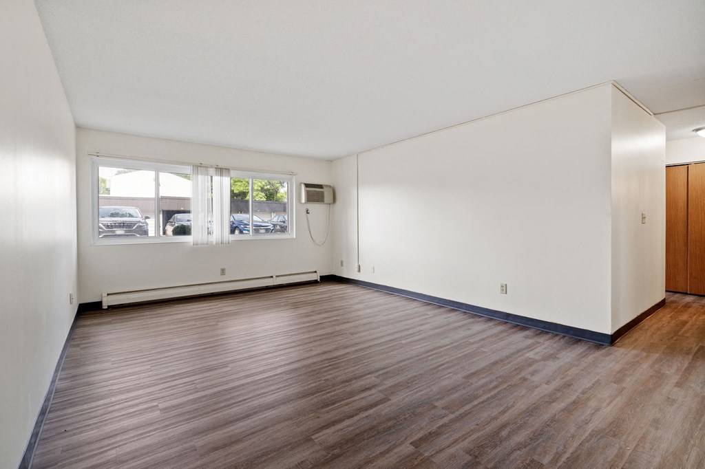 an empty living room with white walls and wood floors