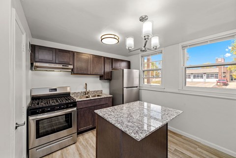 A kitchen with a granite counter top and stainless steel appliances.
