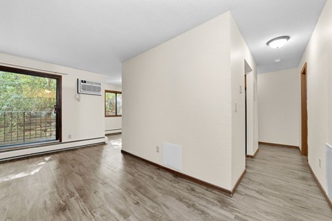 A spacious room with wood flooring and a large window.