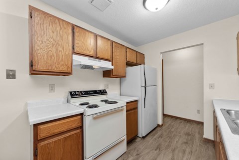 A kitchen with white appliances and wooden cabinets.
